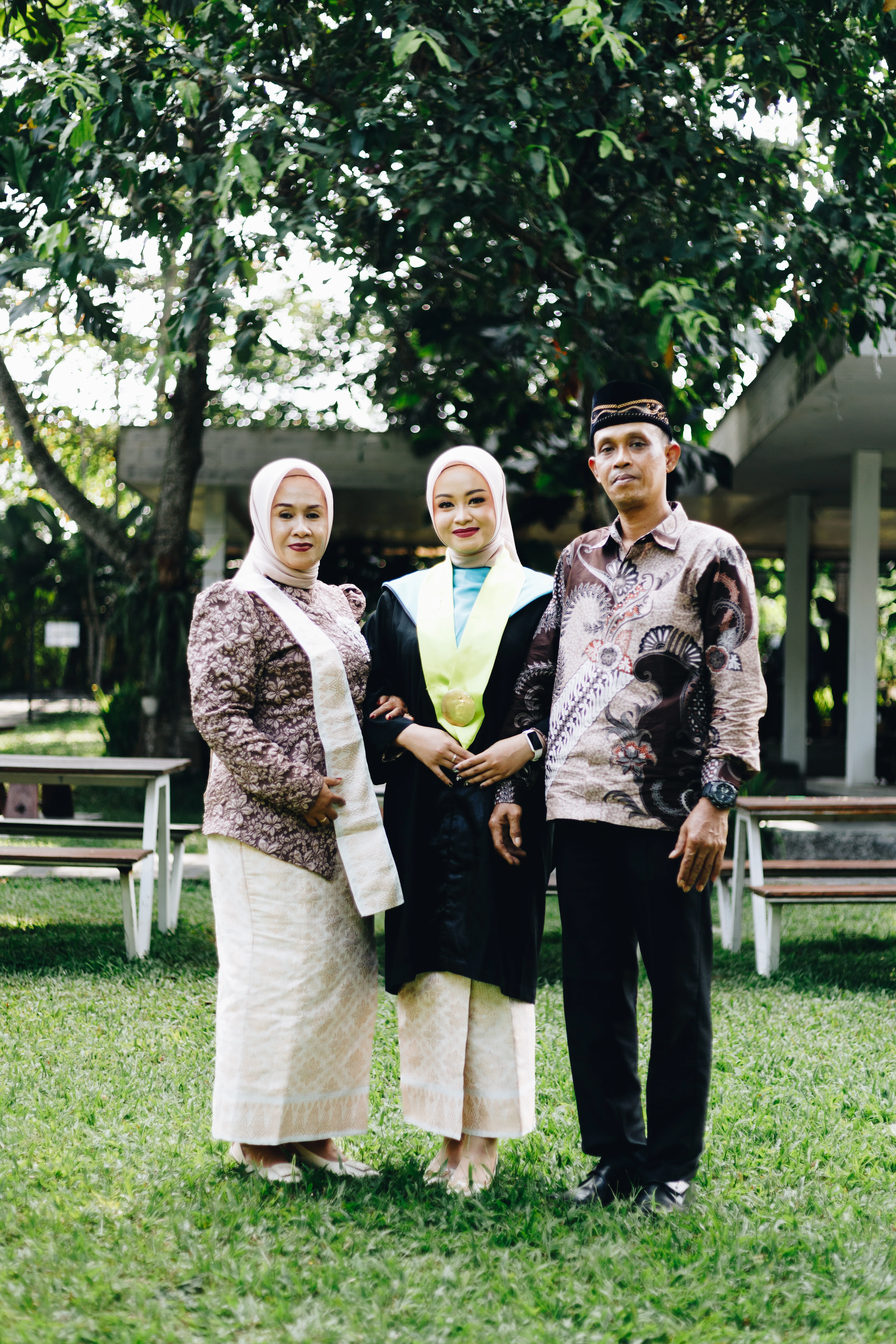 Potret personal wisudawan dengan pose tenang dan busana toga akademis berlatar arsitektur kampus Jogja - Toga & Co.
